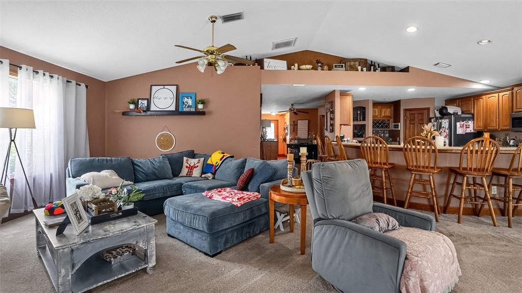 A living room with a blue sectional sofa, gray recliner, and an open kitchen area — 706 MURRAY CIRCLE, LADY LAKE, FL
