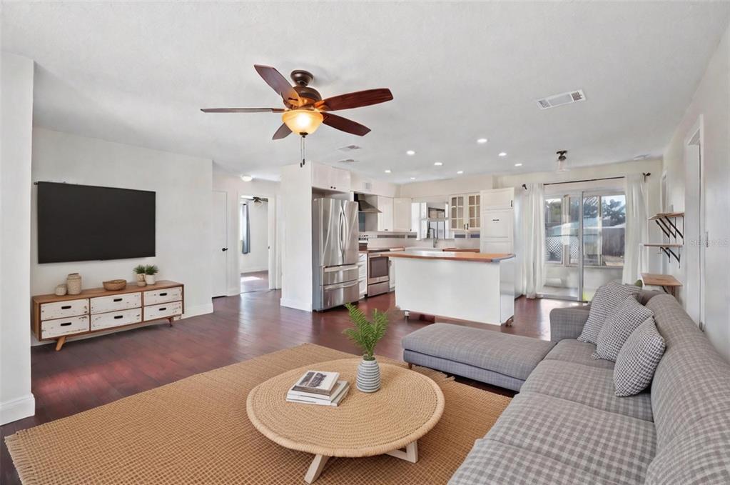 An open-concept living room and kitchen featuring wood flooring, a sectional sofa, and stainless appliances — 1712 THOMAS DRIVE, CLEARWATER, FL