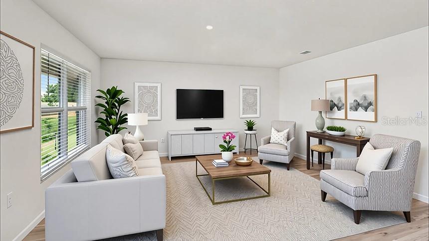 This is a digitally staged living room featuring a sofa, armchairs, and a television console — 8717 BARRAGAN DRIVE, WILDWOOD, FL