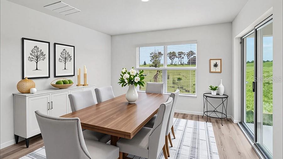 This dining room features a wooden table, gray upholstered chairs, and a sliding glass door — 8717 BARRAGAN DRIVE, WILDWOOD, FL