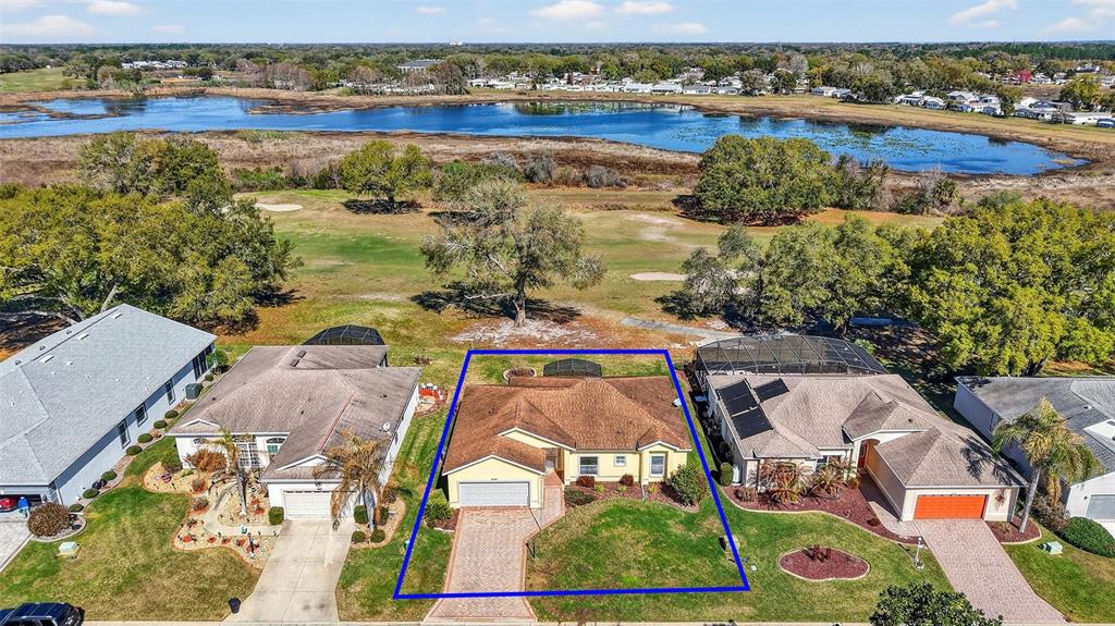 An aerial view shows a yellow single-story house with a brown roof and paved driveway — 5024 LONG MEADOW DRIVE, LEESBURG, FL