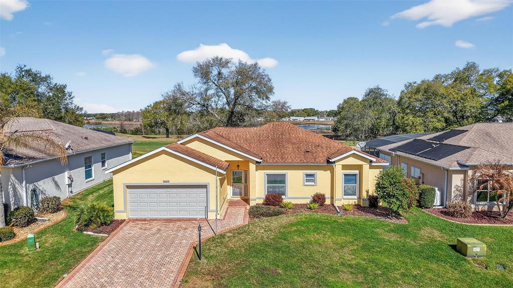 An aerial view of a yellow single-story house with a brick driveway and brown roof — 5024 LONG MEADOW DRIVE, LEESBURG, FL