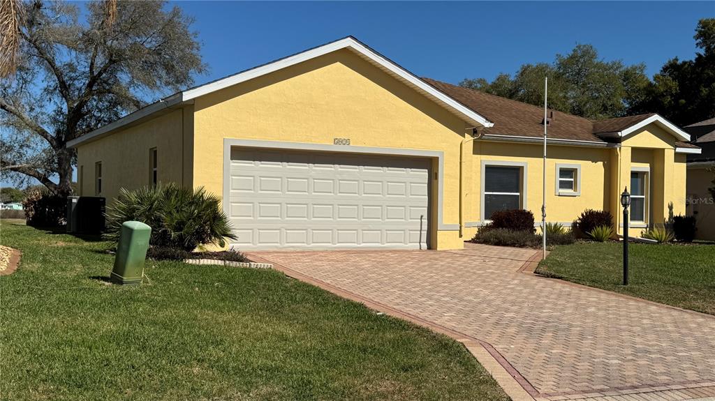 A yellow single-story house features a two-car garage and a paved driveway — 5024 LONG MEADOW DRIVE, LEESBURG, FL