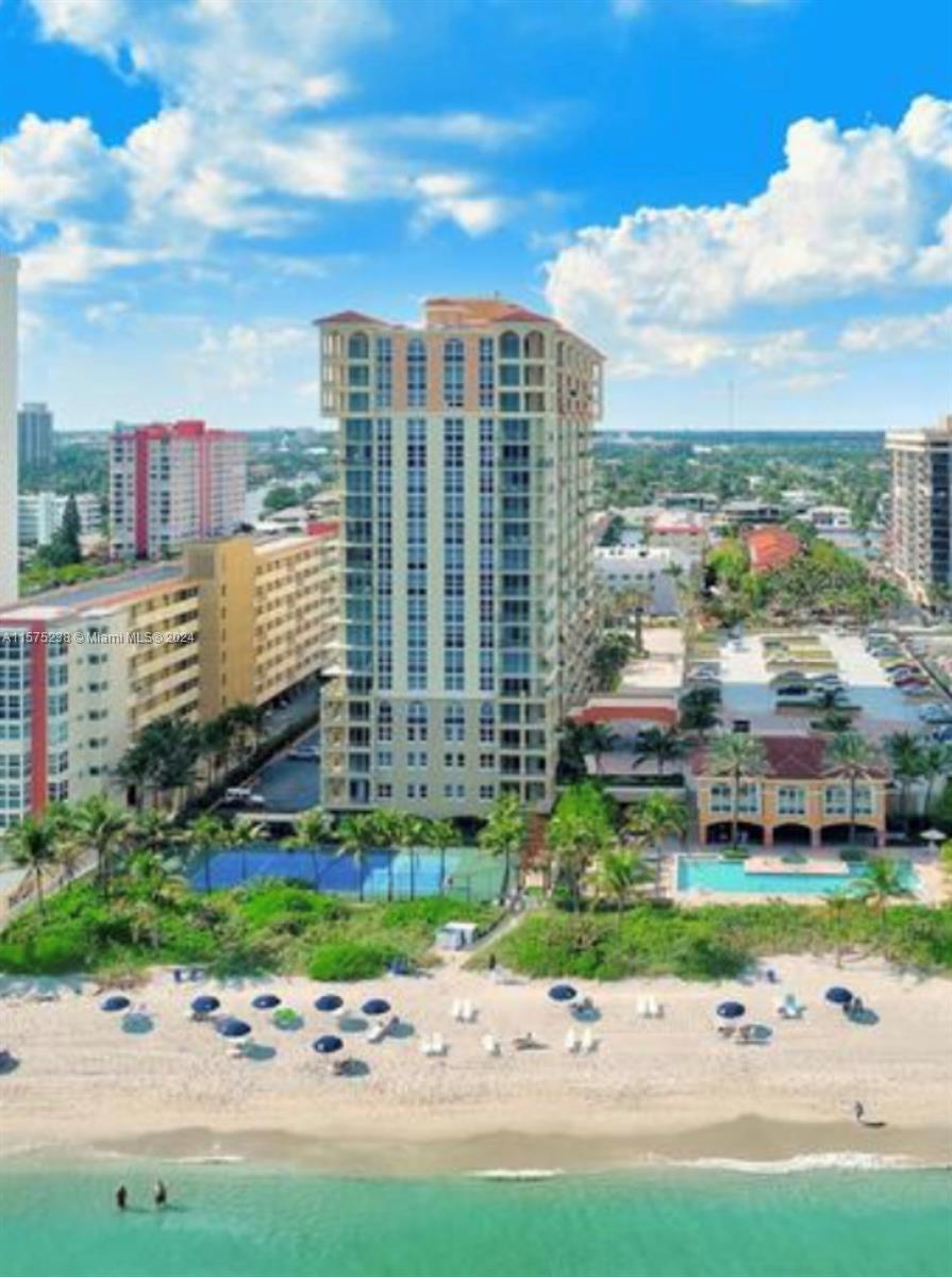 An aerial view shows a tall residential building situated directly on a sandy beach — 2080 S Ocean Dr # 401, Hallandale Beach FL 33009, HALLANDALE BEACH, FL