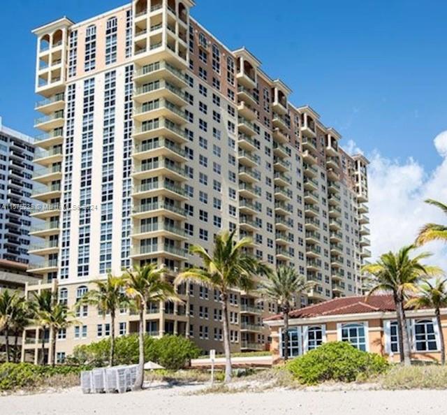 A tall, multi-story residential building stands behind palm trees on a sandy beach — 2080 S Ocean Dr # 401, Hallandale Beach FL 33009, HALLANDALE BEACH, FL
