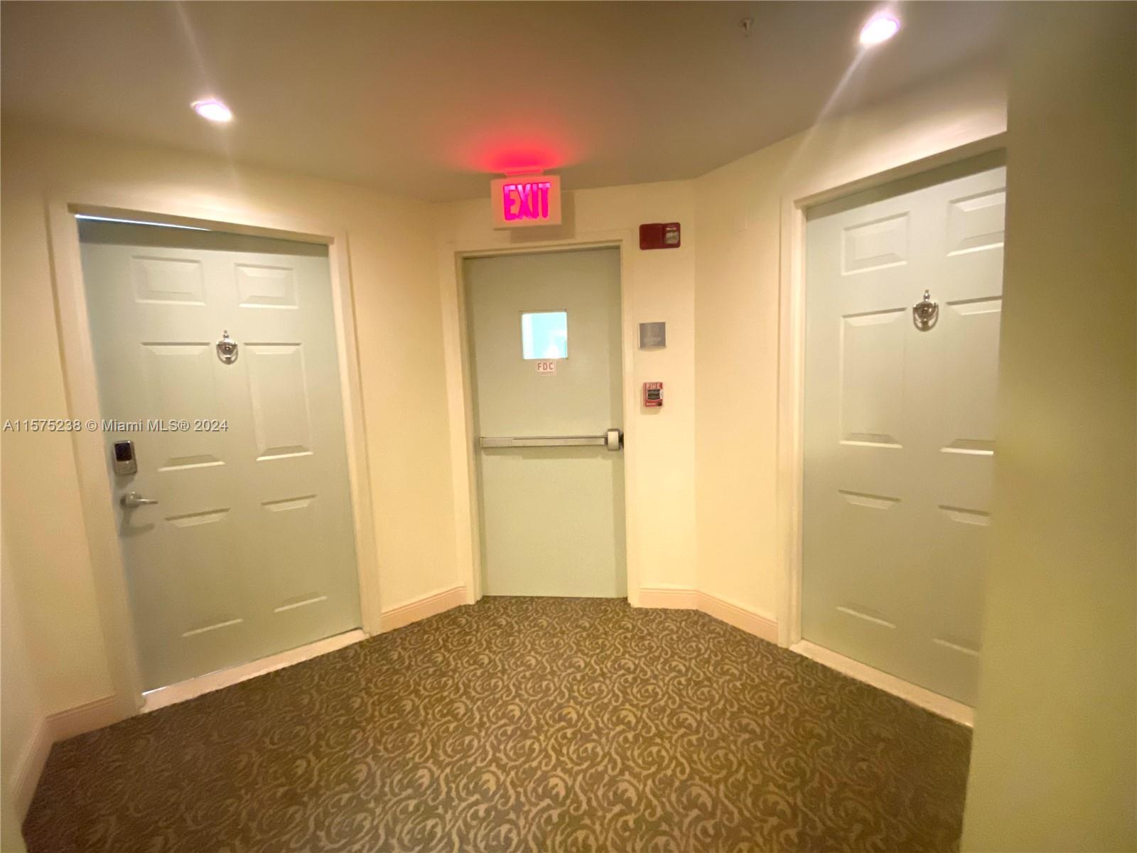 A hallway features three doors, a central exit sign, and patterned carpeting — 2080 S Ocean Dr # 401, Hallandale Beach FL 33009, HALLANDALE BEACH, FL
