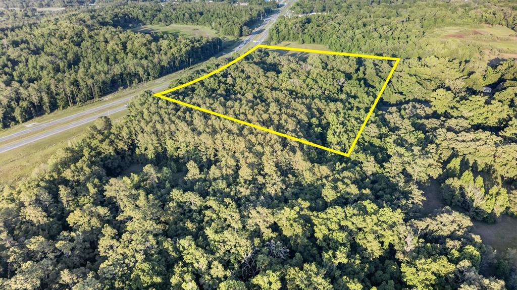 An aerial view shows a wooded plot of land outlined in yellow near a highway — 0 CORTEZ BLVD, BROOKSVILLE, FL