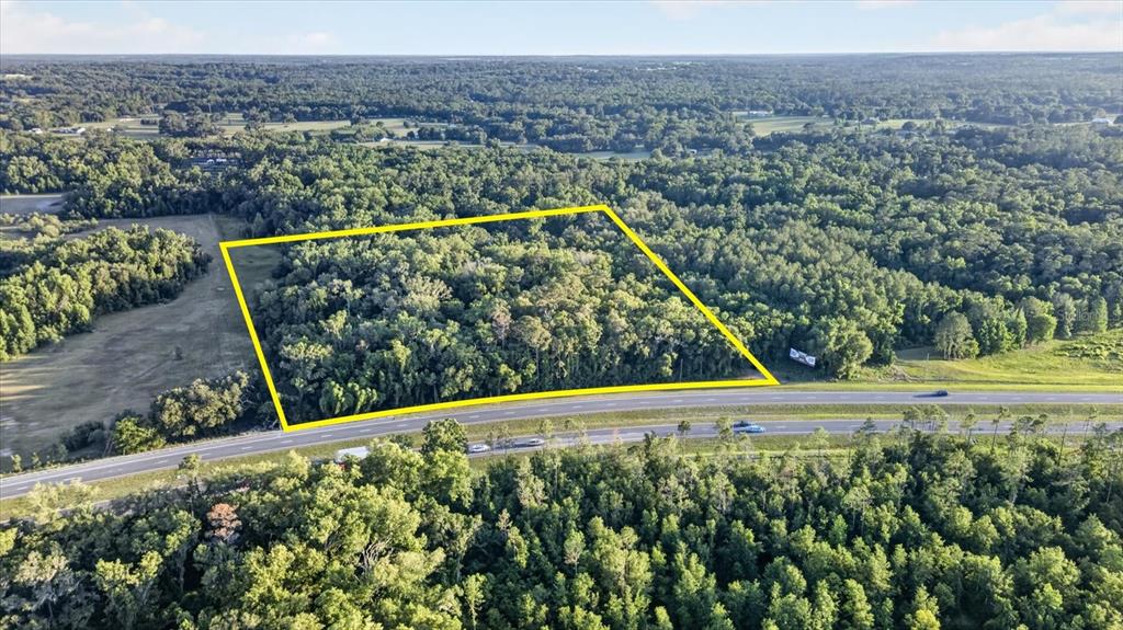 An aerial view shows a rectangular, wooded plot of land bordering a multi-lane highway — 0 CORTEZ BLVD, BROOKSVILLE, FL
