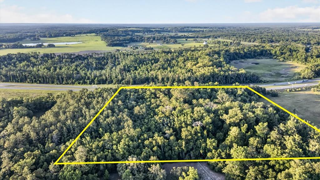An aerial view shows a rectangular plot of wooded land outlined in yellow near a highway — 0 CORTEZ BLVD, BROOKSVILLE, FL
