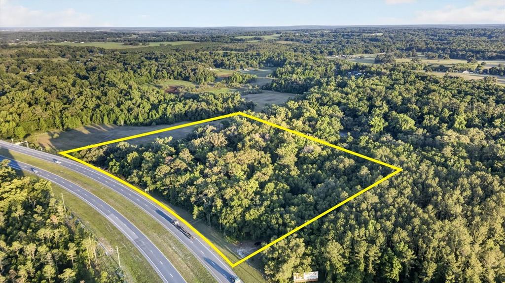 An aerial view shows a wooded plot of land outlined in yellow next to a highway — 0 CORTEZ BLVD, BROOKSVILLE, FL