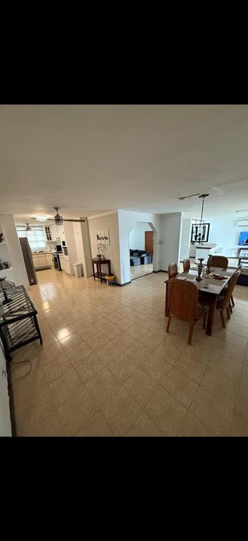 An open-concept living and dining area features light tile flooring and a wooden dining set — R88 CALLE 7, CAROLINA, PR