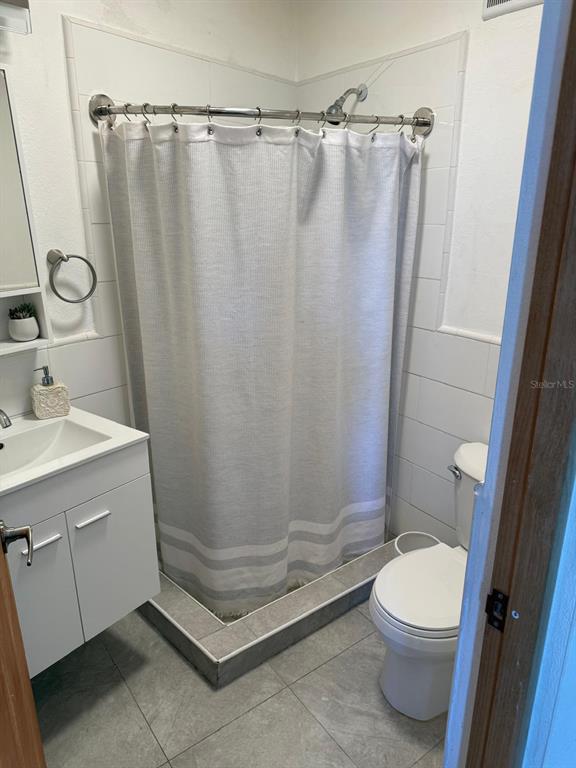 A small bathroom features a white vanity, a tiled shower with a curtain, and a toilet — R88 CALLE 7, CAROLINA, PR