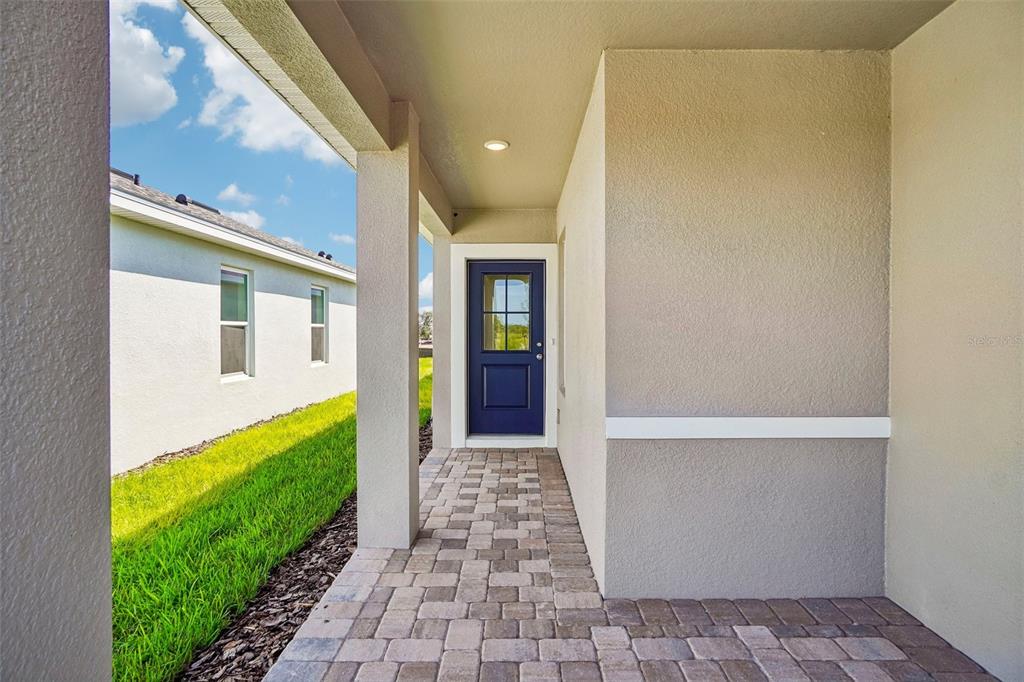 A covered entryway features a blue front door, beige stucco walls, and paver flooring — 341 MEREDITH BOULEVARD, WINTER HAVEN, FL
