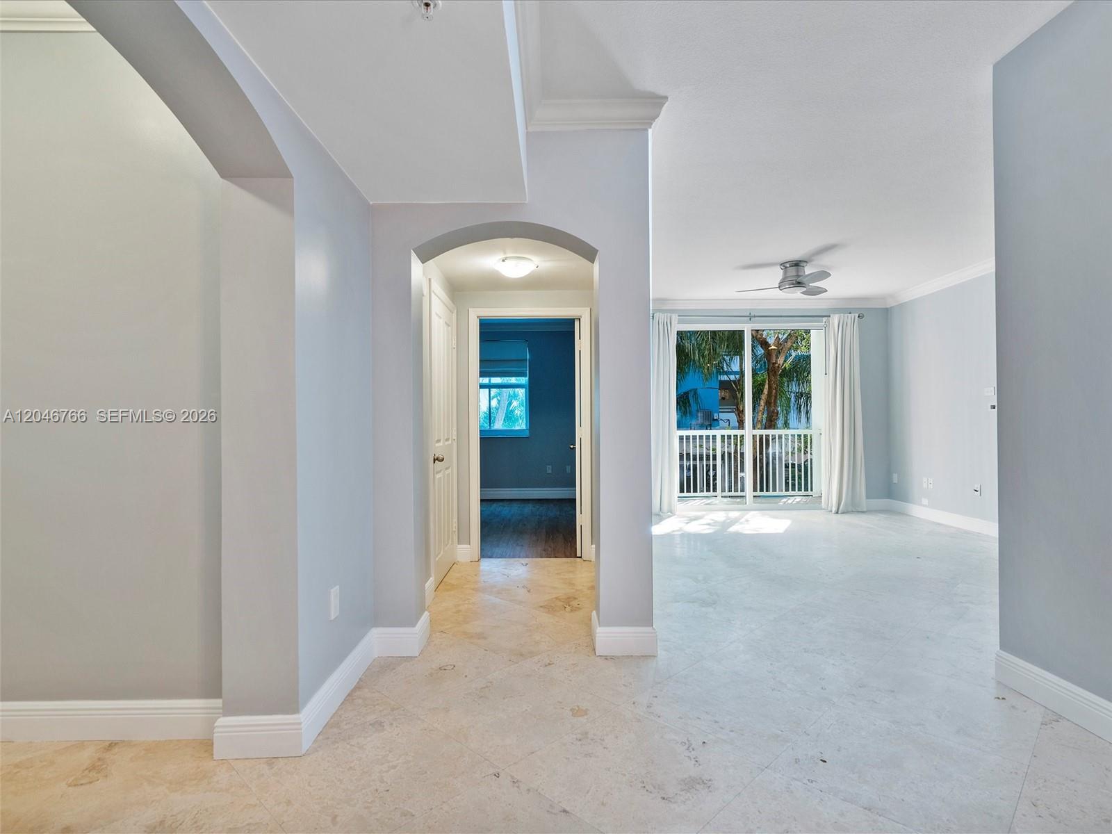 A hallway with light-colored tile floors leads to a bedroom and a bright living area — 9172 Collins Ave # 216, Surfside FL 33154, SURFSIDE, FL