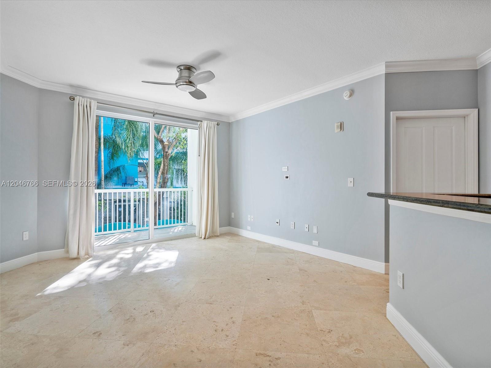 An empty living room features light blue walls, tile flooring, and a sliding glass door — 9172 Collins Ave # 216, Surfside FL 33154, SURFSIDE, FL