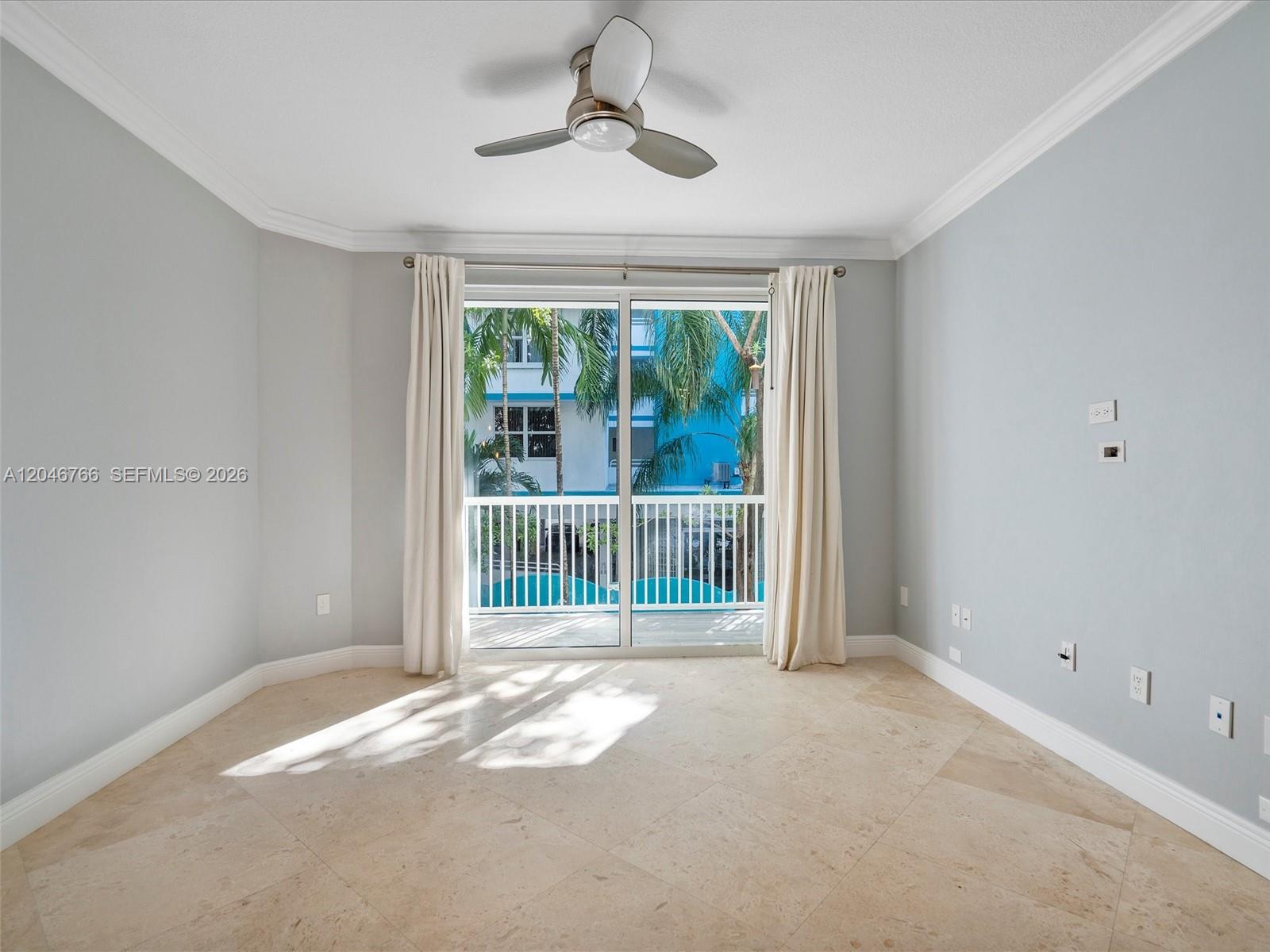 An empty room features light-colored tile flooring, pale blue walls, and a sliding glass door — 9172 Collins Ave # 216, Surfside FL 33154, SURFSIDE, FL