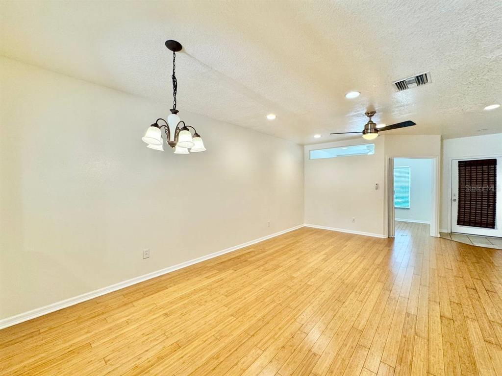 An empty room with light wood flooring, a ceiling fan, and a hanging light fixture — 12381 FOXMOOR PEAK DRIVE, RIVERVIEW, FL