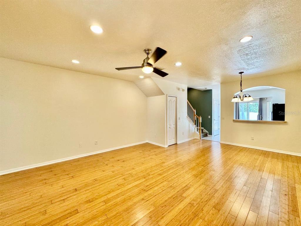 An empty living room features light wood flooring, a ceiling fan, and a staircase — 12381 FOXMOOR PEAK DRIVE, RIVERVIEW, FL