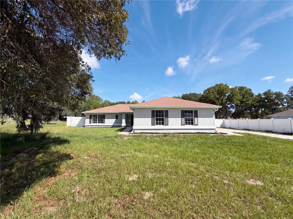 A single-story house with a light-colored exterior and a red roof sits on a grassy lot — 6297 SW 148TH STREET, OCALA, FL
