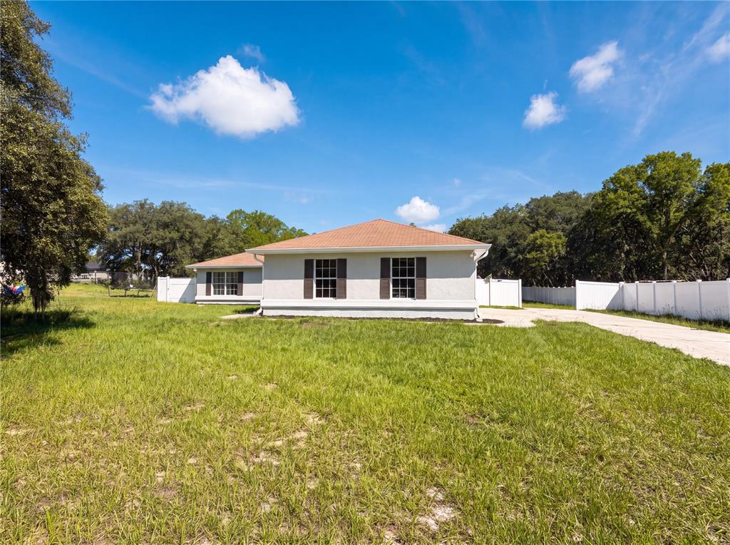 A single-story house with a tan roof and white exterior sits on a grassy lot — 6297 SW 148TH STREET, OCALA, FL