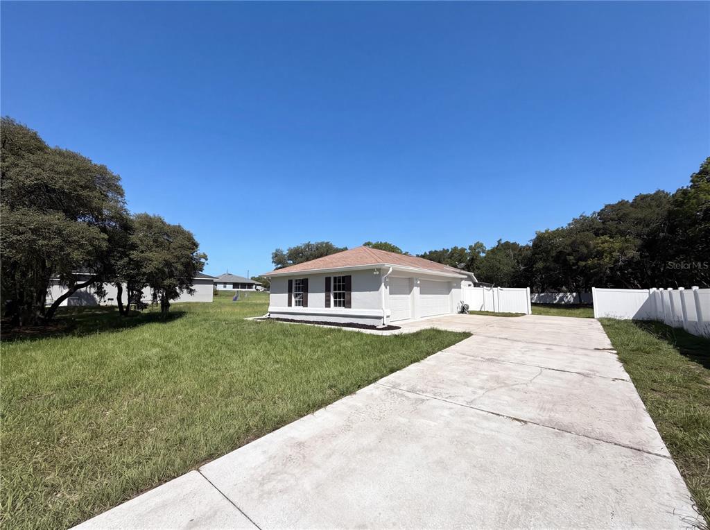 A white house with a two-car garage and a concrete driveway sits on a grassy lot — 6297 SW 148TH STREET, OCALA, FL