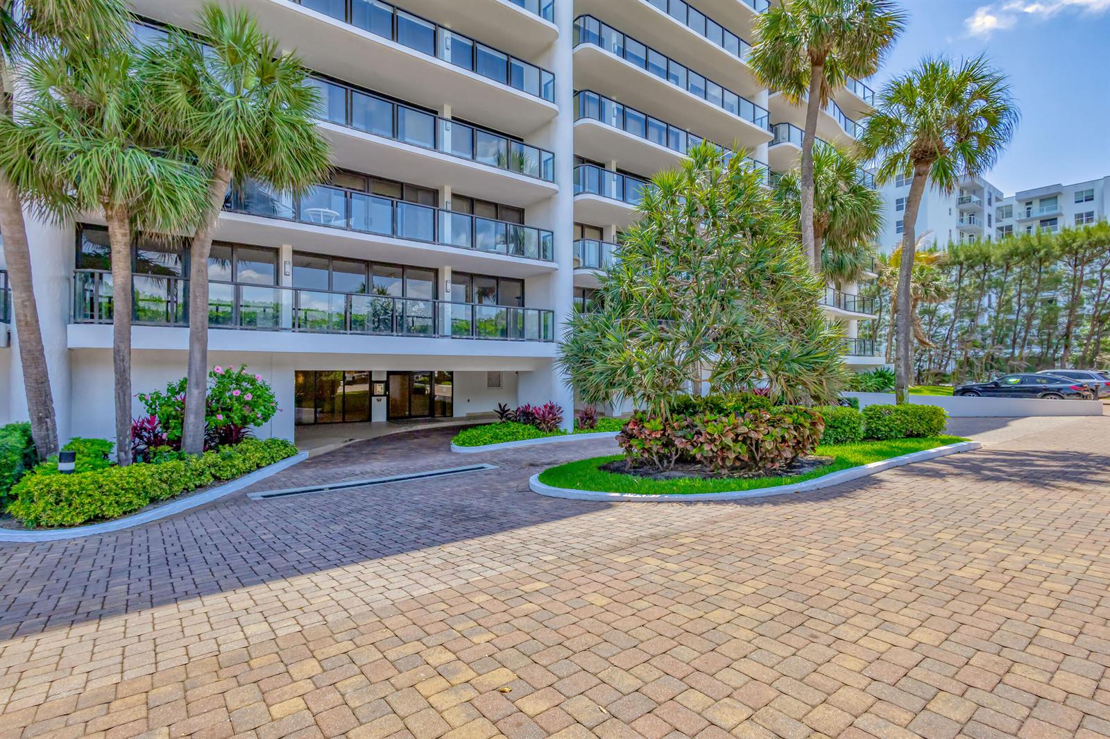 A paved driveway leads to the entrance of a multi-story apartment building with palm trees — 3440 S Ocean Boulevard S # 401, Palm Beach FL 33480, PALM BEACH, FL