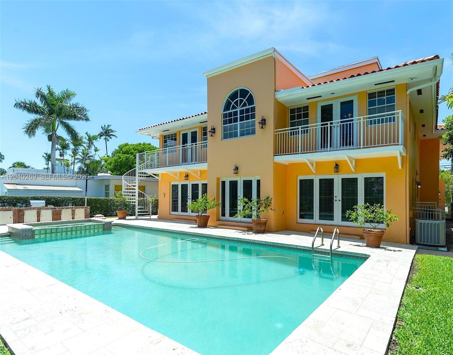 The exterior of a two-story yellow house features a swimming pool and a spiral staircase — 5309 Alton Rd, Miami Beach FL 33140, MIAMI BEACH, FL
