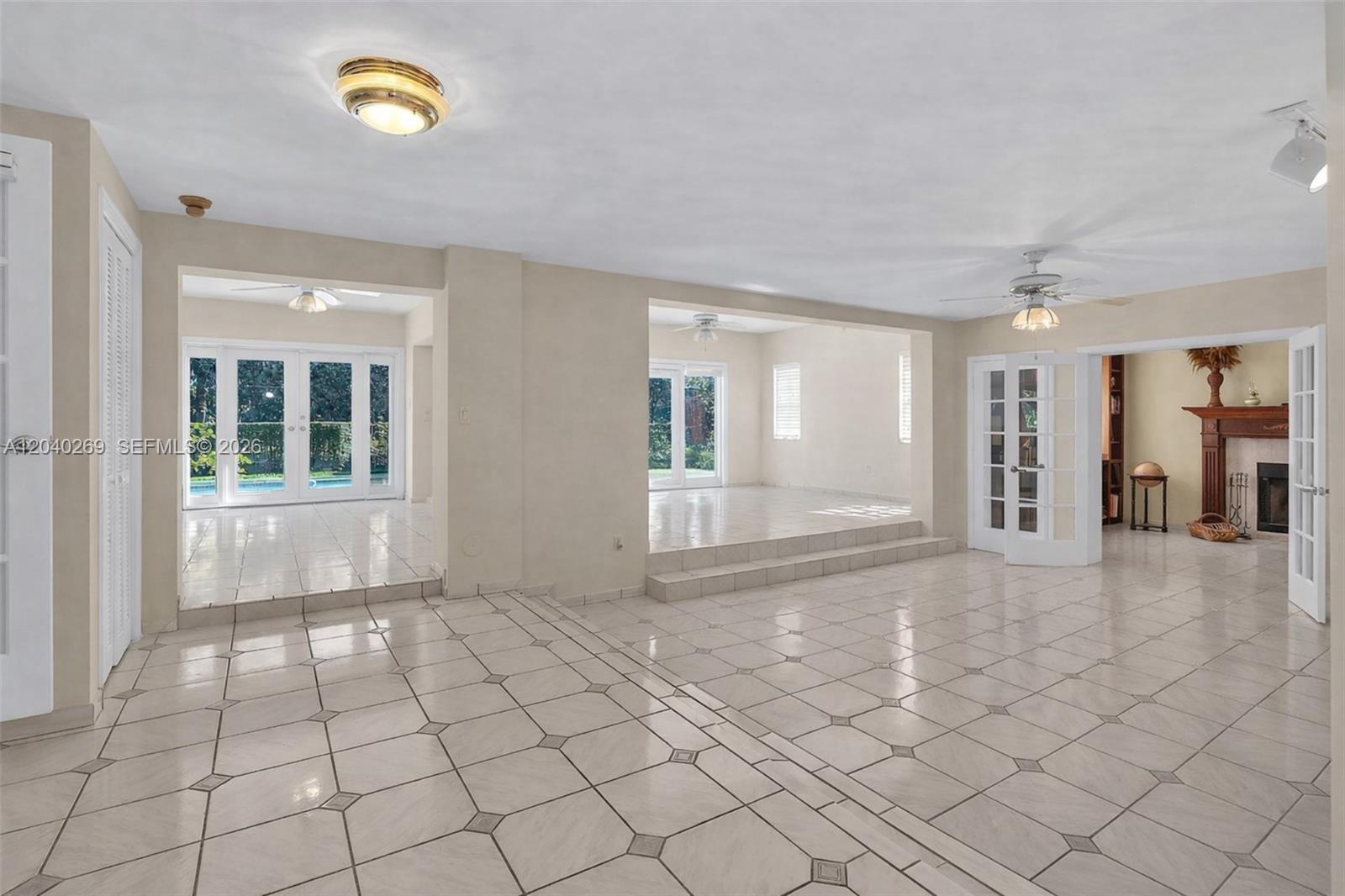 A spacious living area features light-colored tile flooring, multiple step-up rooms, and French doors — 5309 Alton Rd, Miami Beach FL 33140, MIAMI BEACH, FL