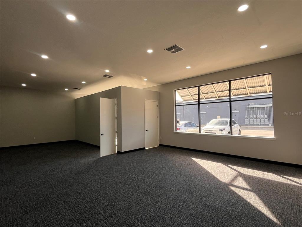 An empty office space features gray carpet, recessed lighting, and a large window — 2019 21 STREET NW, WINTER HAVEN, FL