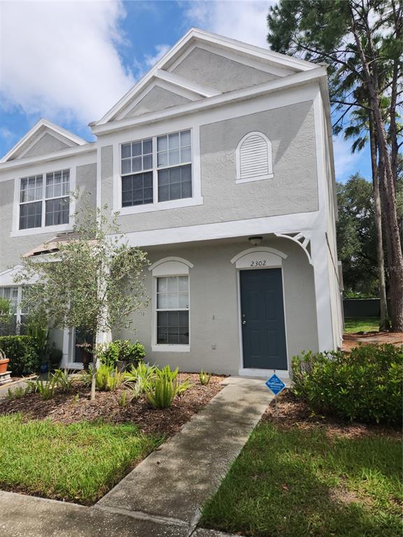 A two-story gray townhouse with a dark blue front door and a concrete walkway — 2302 LAKE WOODBERRY CIRCLE, BRANDON, FL
