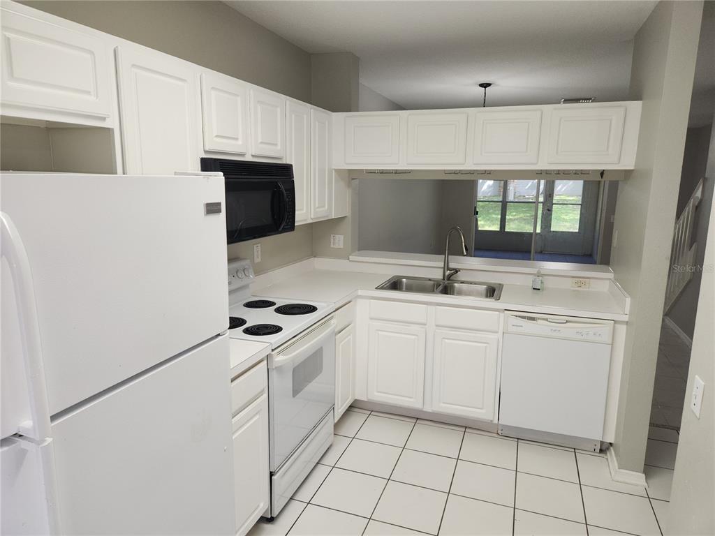 A kitchen with white cabinets, white appliances, a double sink, and white tile flooring — 2302 LAKE WOODBERRY CIRCLE, BRANDON, FL