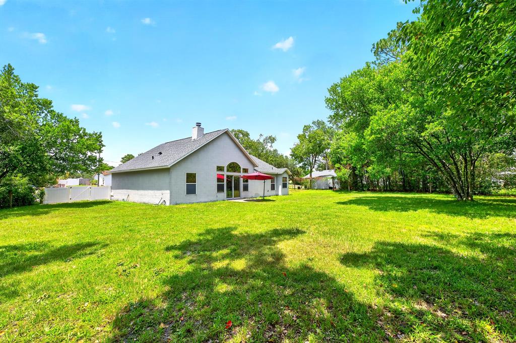 A single-story house with a gray exterior sits on a large, grassy backyard lot — 2911 MALCOLM DRIVE, DELTONA, FL