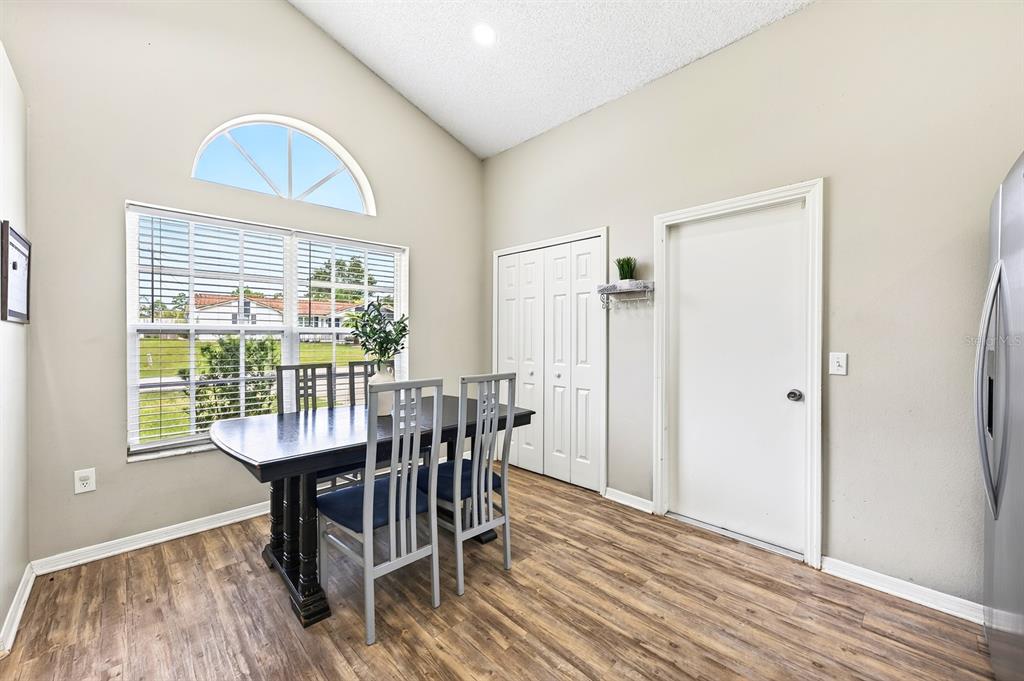 A dining area features wood-look flooring, a vaulted ceiling, and a window with an arched transom — 2911 MALCOLM DRIVE, DELTONA, FL