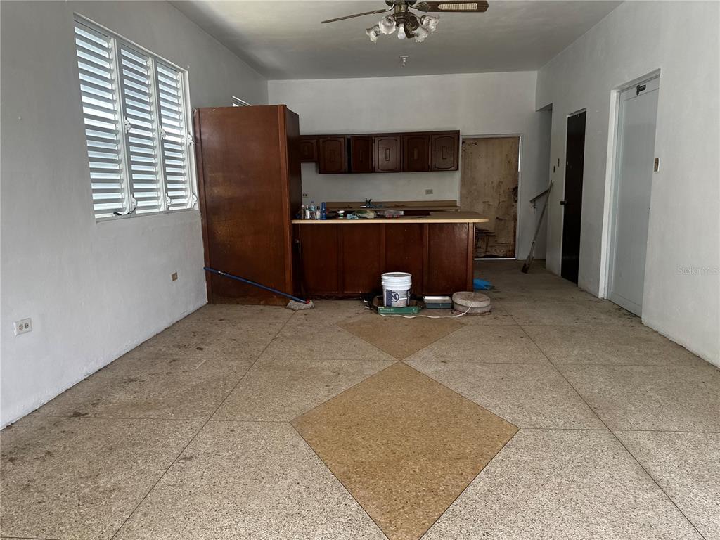 An interior view of a kitchen and living area with terrazzo flooring and wooden cabinets — D URB. EL EDEN D-7, COAMO, PR