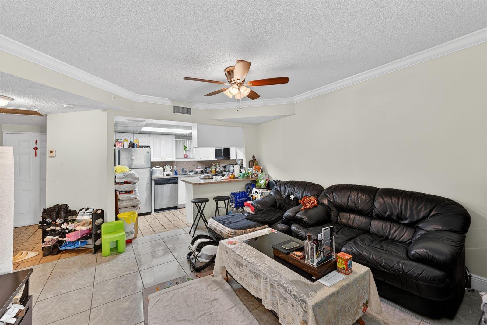 A living room with tile flooring, a black leather sofa, and an open kitchen area — 8290 Lake Drive # 305, Doral FL 33166, DORAL, FL