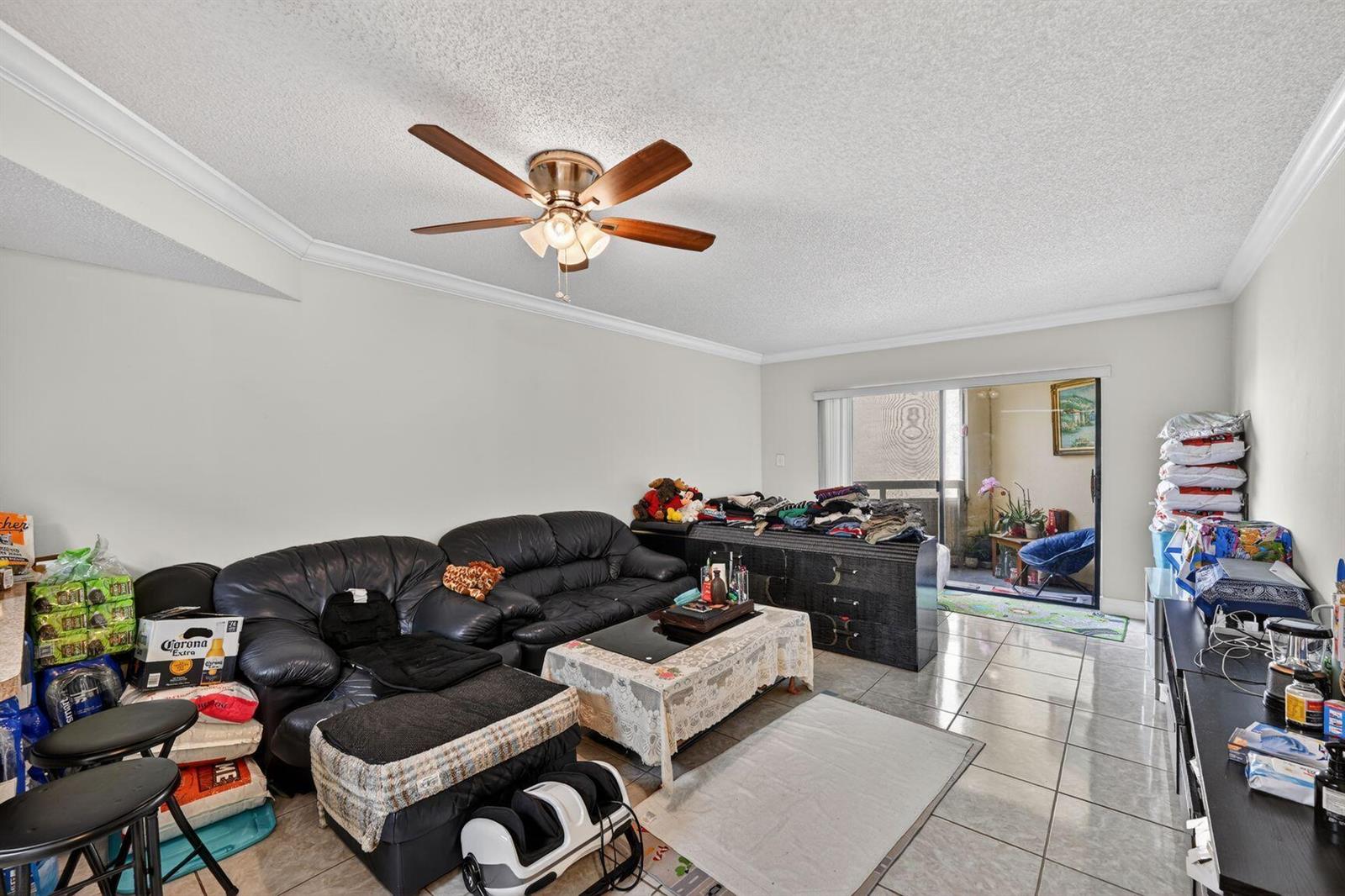 A living room with tile floors, a ceiling fan, a black sofa, and a balcony — 8290 Lake Drive # 305, Doral FL 33166, DORAL, FL