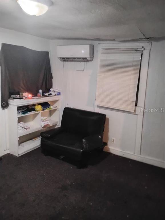 A room with a black chair, a white bookshelf, a wall-mounted air conditioner, and a window — 2531 WEBER STREET, LAKELAND, FL