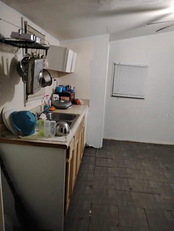 A small kitchen features a stainless steel sink, wooden cabinets, and hanging cookware — 2531 WEBER STREET, LAKELAND, FL