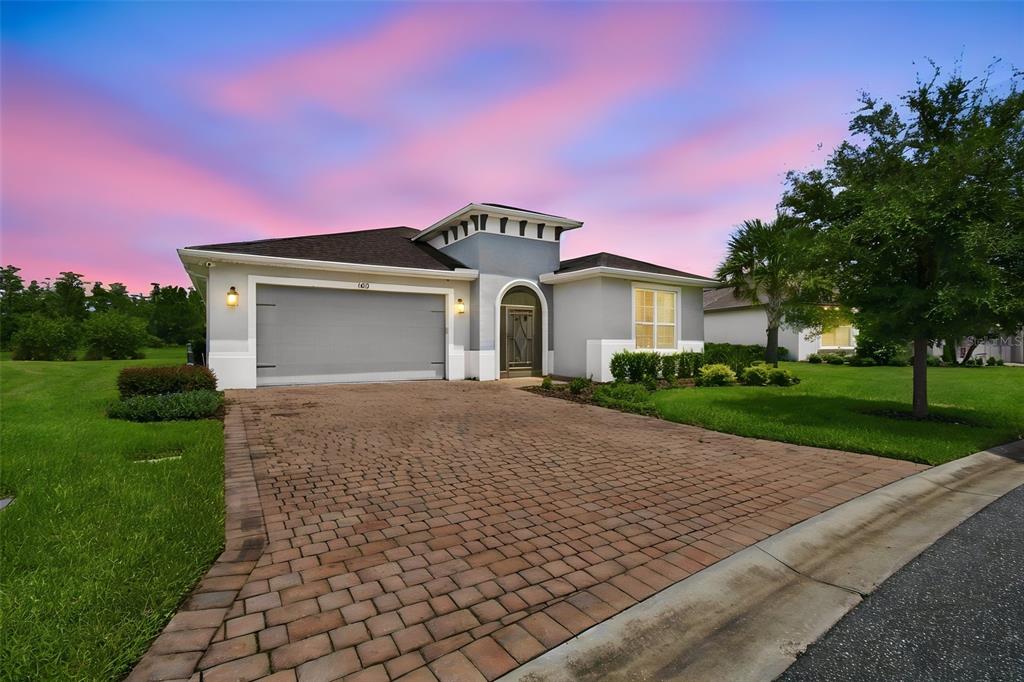 A single-story house with a gray exterior, a brick paver driveway, and a two-car garage — 163 OLYMPUS WAY, KISSIMMEE, FL