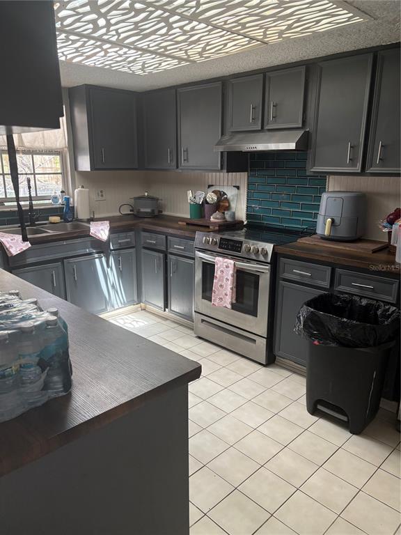 A kitchen features gray cabinets, dark wood countertops, a teal subway tile backsplash, and stainless appliances — 94 GLASS COURT, PORT ORANGE, FL