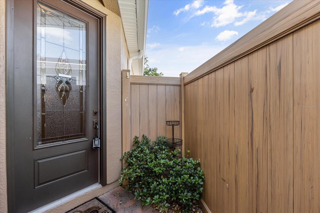 A brown front door with a decorative glass insert sits beside a wooden privacy fence — 126 BAYOU BEND ROAD, GROVELAND, FL