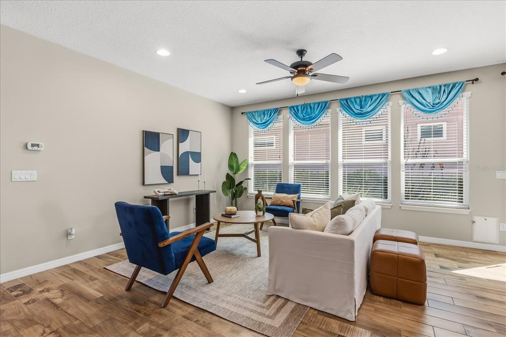 A living room features a white sofa, blue armchairs, a coffee table, and window valances — 126 BAYOU BEND ROAD, GROVELAND, FL