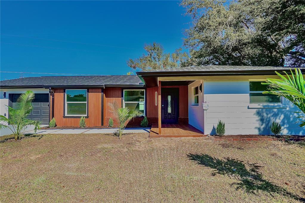 A single-story house features a mix of white siding, wood paneling, and a covered entryway — 1797 BIRCH DRIVE, VENICE, FL