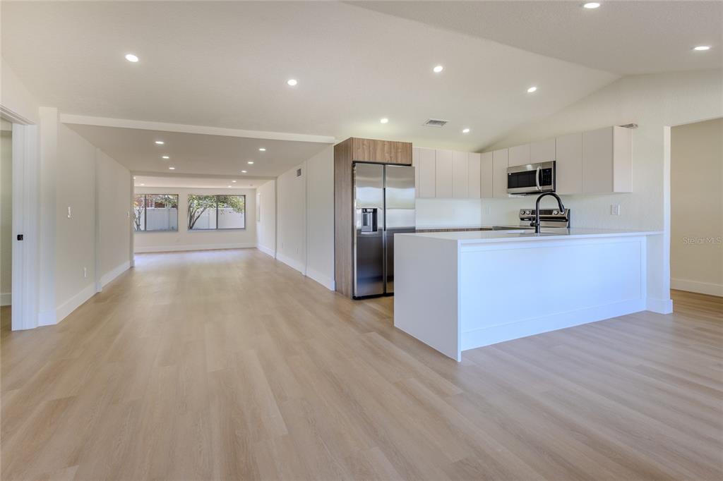 A modern open-concept kitchen and living area featuring light wood flooring and white cabinetry — 4502 S GRADY AVENUE, TAMPA, FL