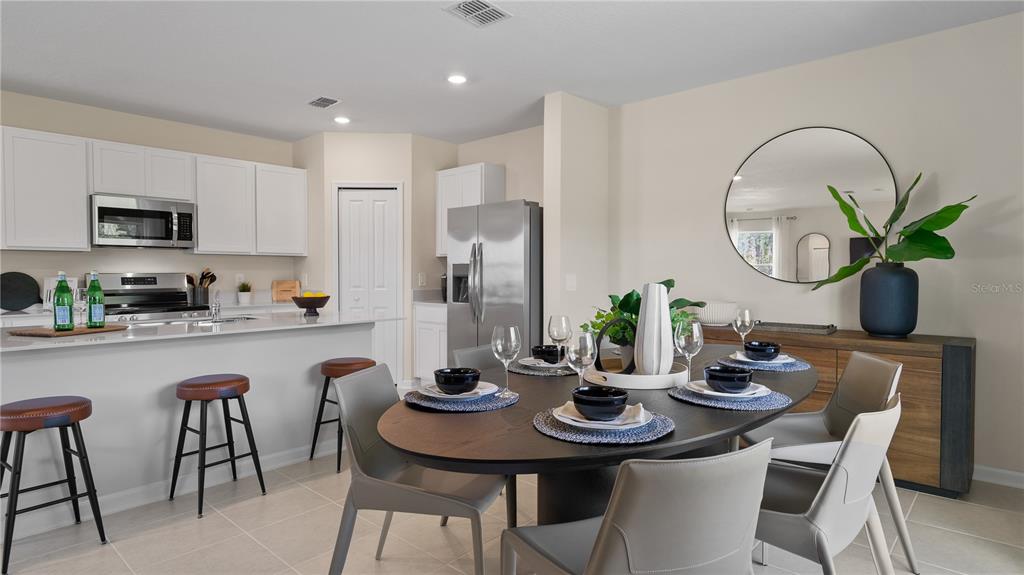 A dining area with an oval table and chairs sits adjacent to a modern kitchen — 6253 BOTTICELLA BOULEVARD, WINTER HAVEN, FL