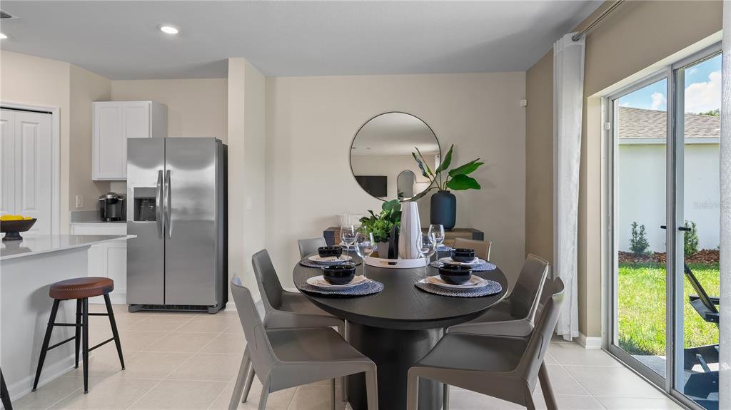 A dining area features a dark oval table, gray chairs, and a stainless steel refrigerator — 6253 BOTTICELLA BOULEVARD, WINTER HAVEN, FL
