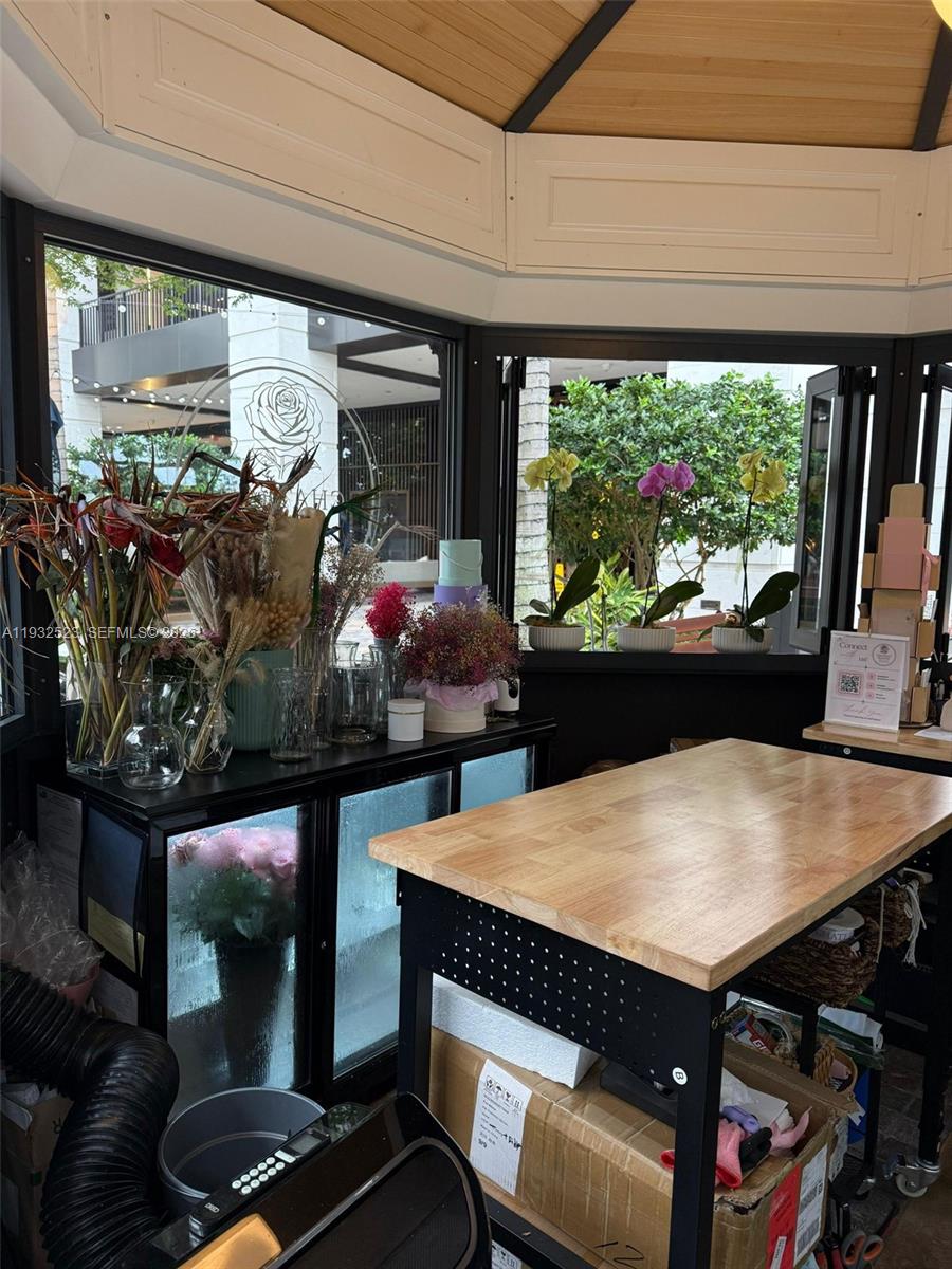 A floral shop interior features a wooden work table, glass display case, and potted orchids — 3011 Ponce de Leon Blvd, Coral Gables FL 33134, CORAL GABLES, FL