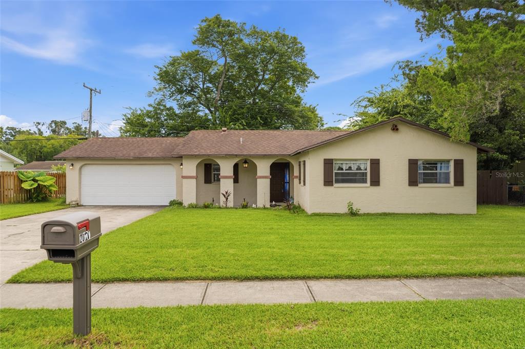 A single-story house with a beige stucco exterior, a two-car garage, and a front lawn — 2021 ORIOLE LANE, SOUTH DAYTONA, FL