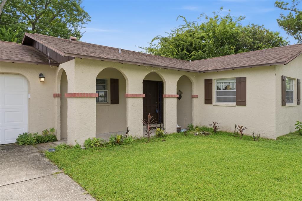 A single-story house with a stucco exterior, arched front porch, and a brown shingled roof — 2021 ORIOLE LANE, SOUTH DAYTONA, FL