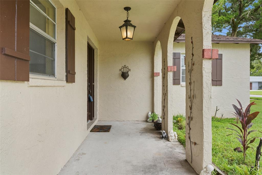 A covered front porch features arched openings, stucco walls, and a hanging lantern light fixture — 2021 ORIOLE LANE, SOUTH DAYTONA, FL